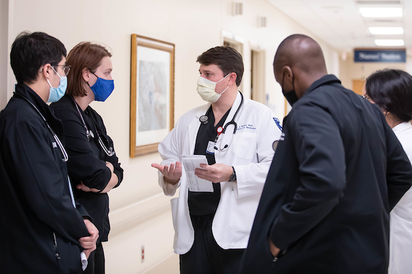 J. Riley Alef, M3, and a trio of other medical students discuss patient care with Dr. Danielle Foster.